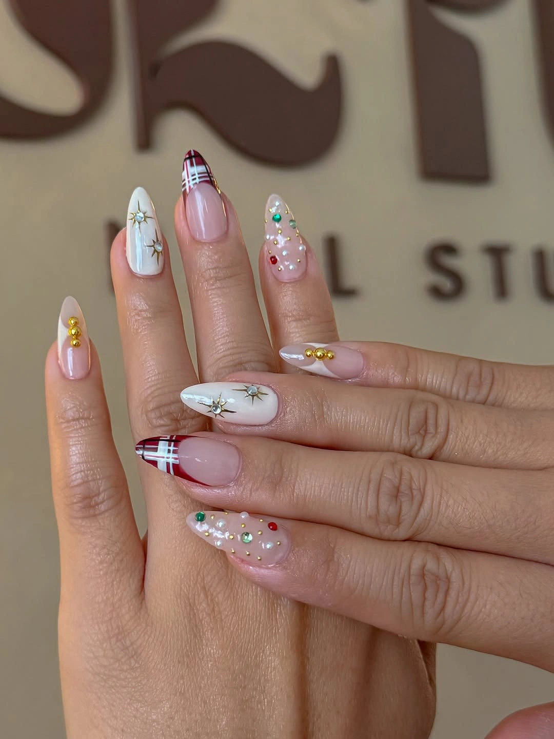 Long pink and white nails with plaid tips, starbursts, and colorful embellishments.