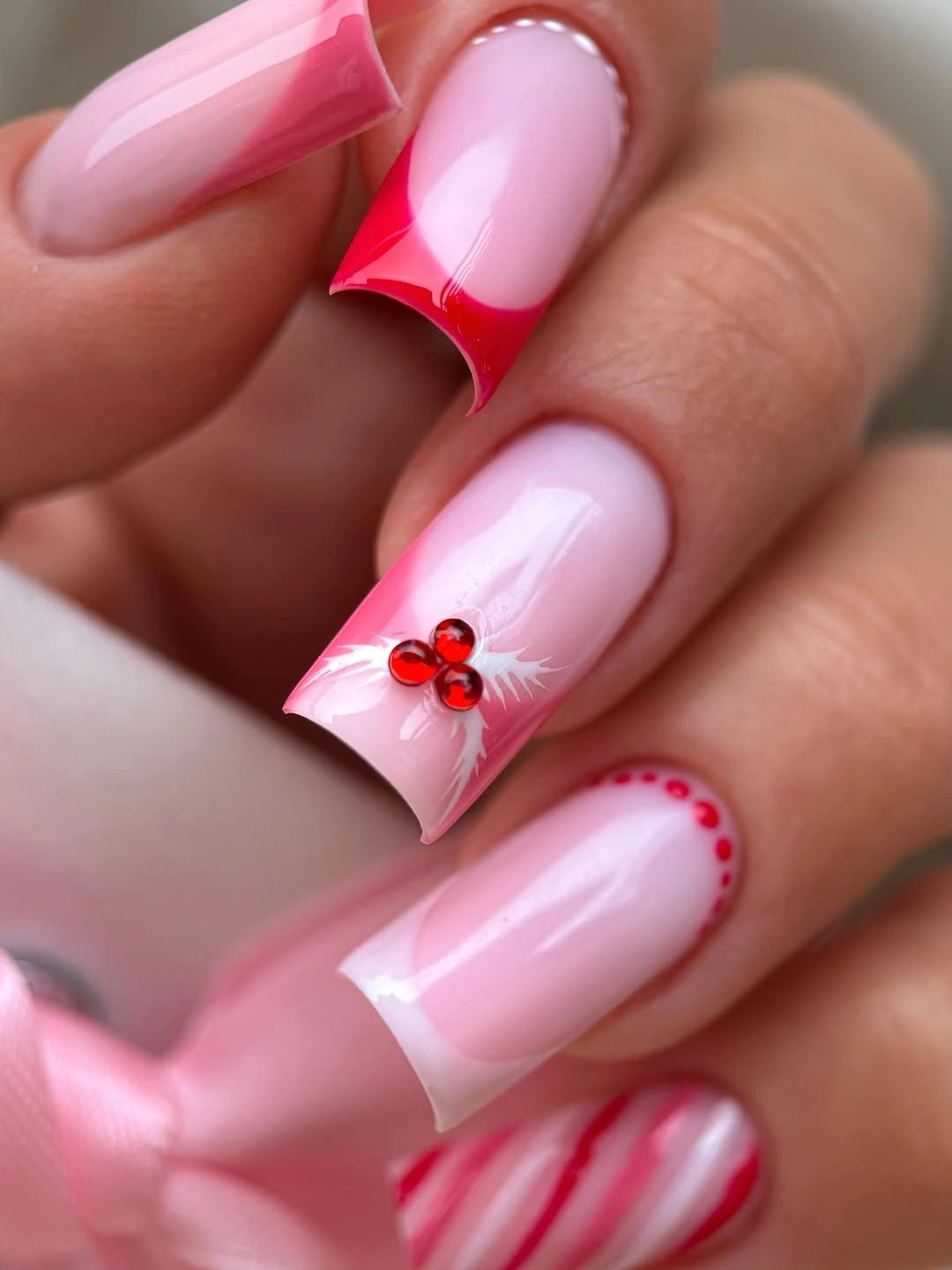 Long square pink nails with red tips, white branches, and striped accents.