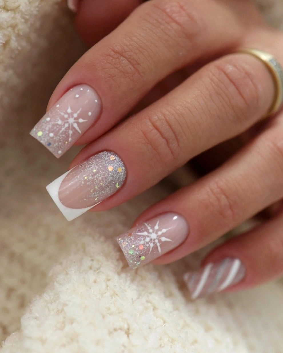 Long square pink nails with white snowflakes, French tips, and iridescent glitter.
