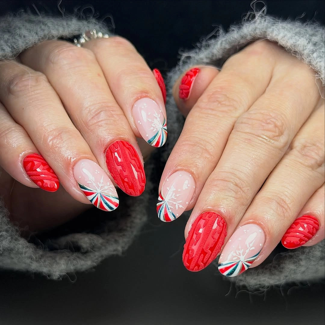 Rounded nails with textured red accents, pale pink snowflakes, and multicolor tips.