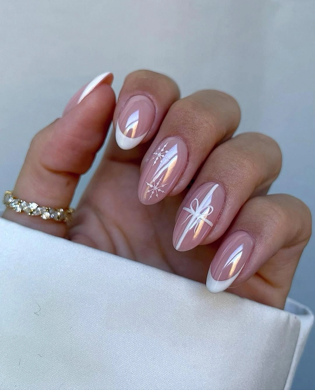 Sheer pink almond nails with white French tips, bows, and snowflake line art.