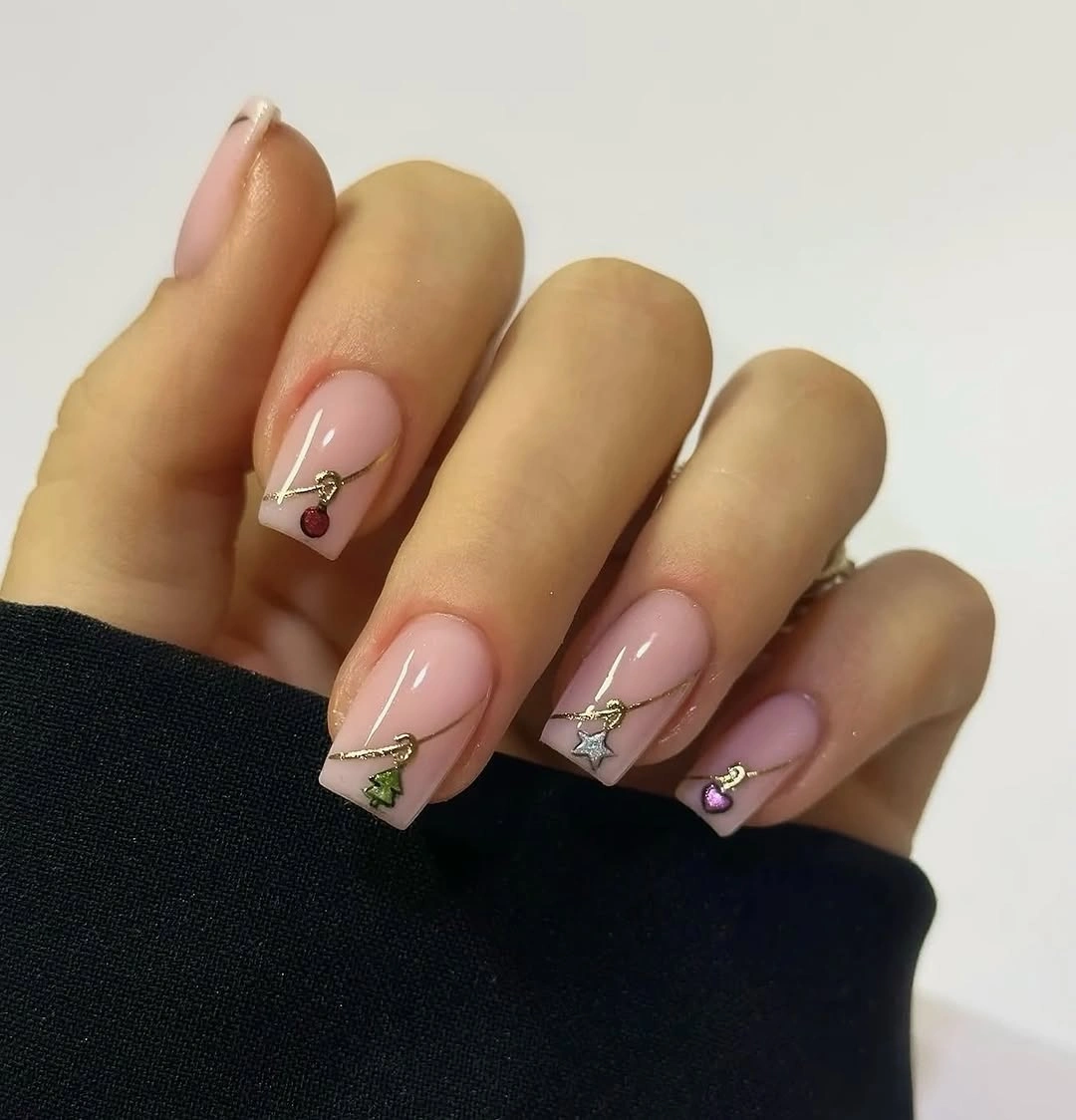 Long nude pink nails with fine gold lines and tiny colorful ornaments.