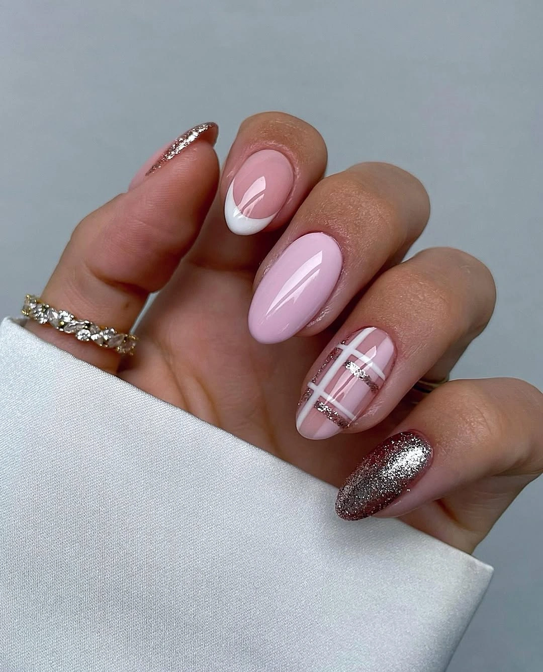 Glossy pale pink nails with white tips, crossed lines, and silver glitter.