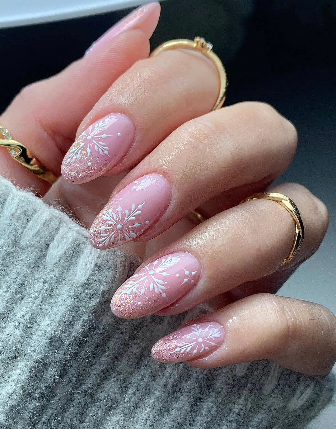 Pink almond nails with white snowflakes and shimmering silver glitter tips.