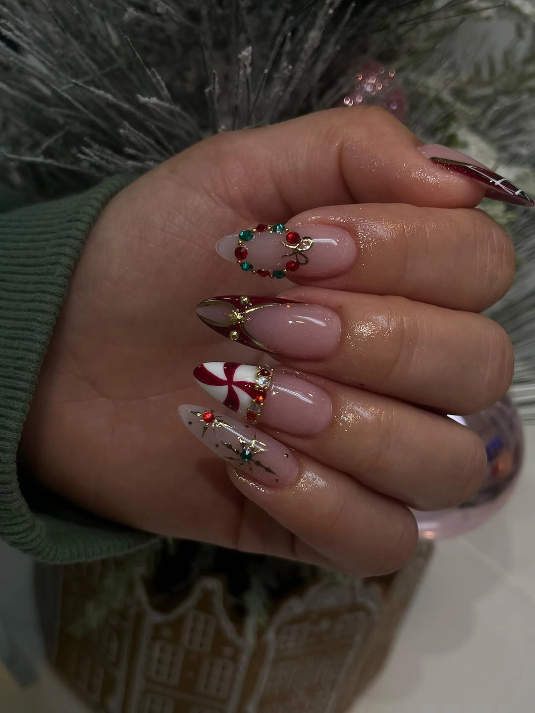 Pink almond nails with candy-cane stripes and multicolored wreath-like nail details.