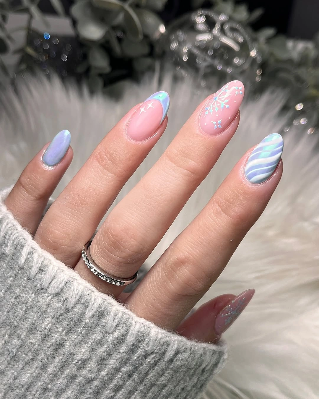 Pastel lavender almond nails with blue stripes and white snowflakes.
