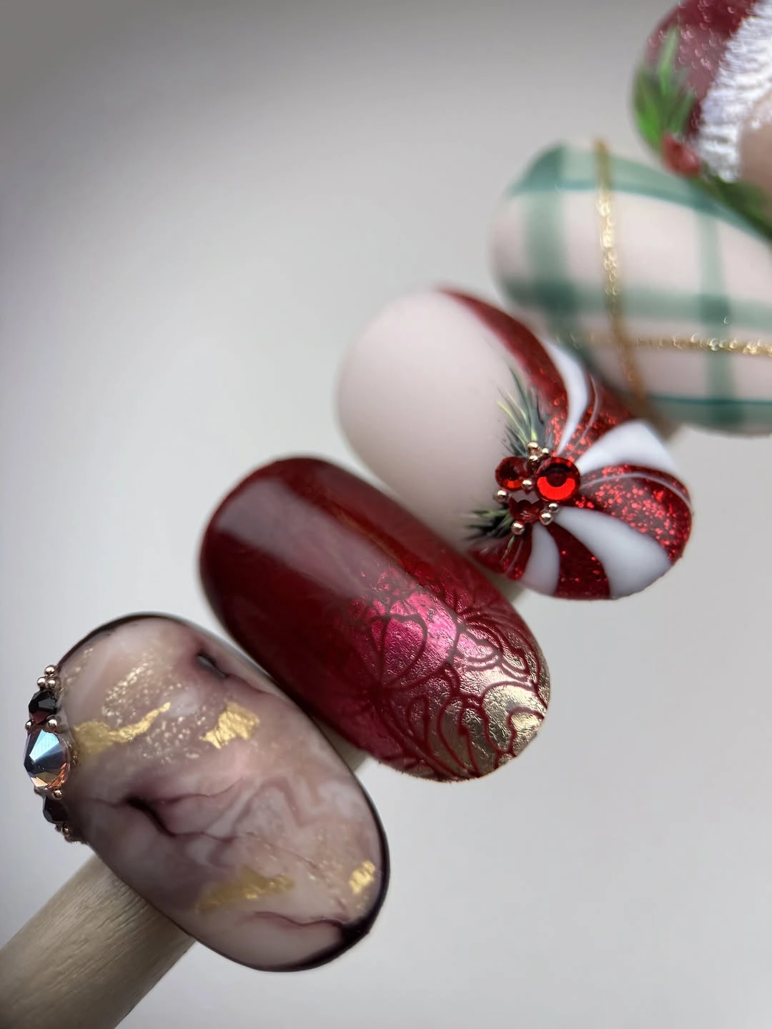 Displayed nail swatches with burgundy patterns, green plaid, and red candy stripes.